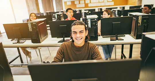 Young students using computers inside technology class at school room